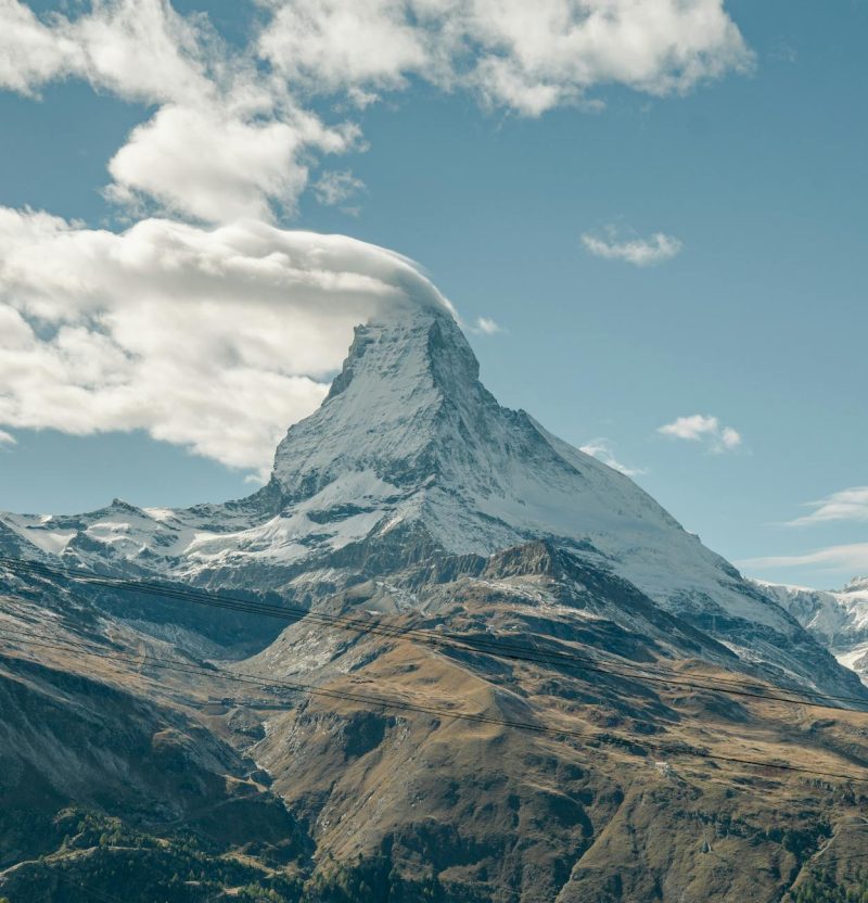 Stunning view of the Matterhorn in Zermatt, Switzerland with a cloud-capped peak on a clear day.