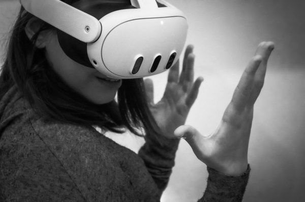 Black and white image of a woman wearing a VR headset, engaged in a virtual reality experience.