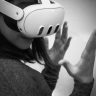 Black and white image of a woman wearing a VR headset, engaged in a virtual reality experience.