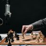 A robotic arm plays chess against a human, symbolizing AI innovation and strategy.