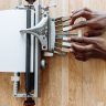 Close-up of hands using a vintage assistive Braille typewriter on a wooden table.