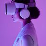 Side profile of a woman wearing VR goggles in a studio with purple lighting, embodying future tech.
