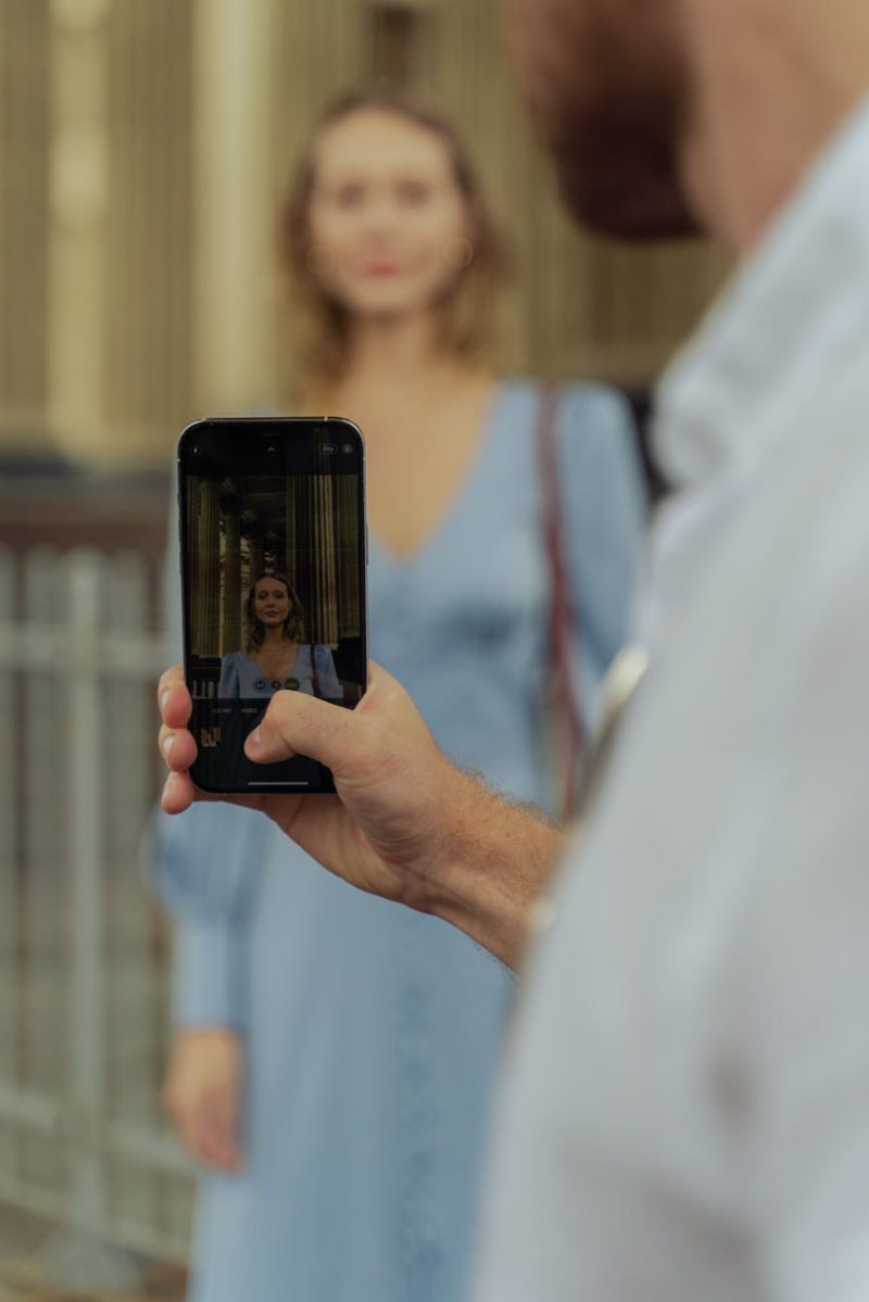 A smartphone capturing a woman's portrait outdoors with blurred background.