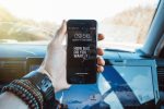 Close-up of a hand holding a smartphone in a car, highlighting technology and motivation.
