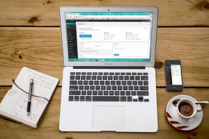 A cozy home office scene with a laptop, notebook, smartphone, and coffee, perfect for productivity.