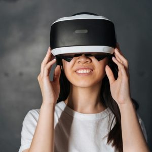 Smiling young woman immersed in virtual reality, wearing VR headset indoors.