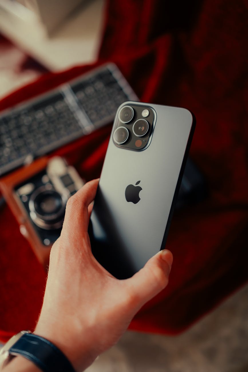 Close-up of a modern smartphone held above a vintage camera on a textured background.
