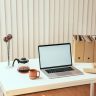 A clean and minimalistic office setup with a laptop, coffee carafe, and stylish decor.