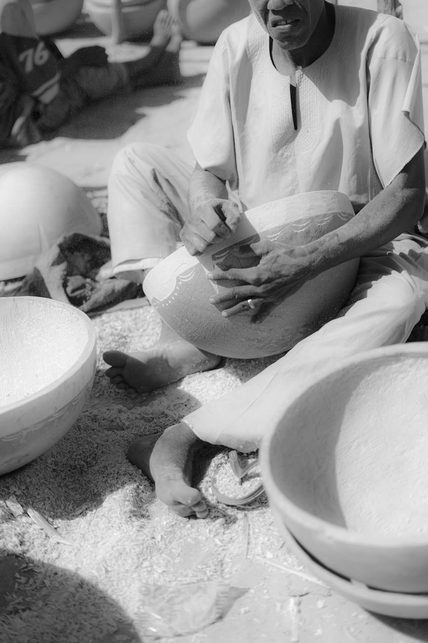 A craftsman carving a wooden bowl in a vibrant Nigerian market setting.